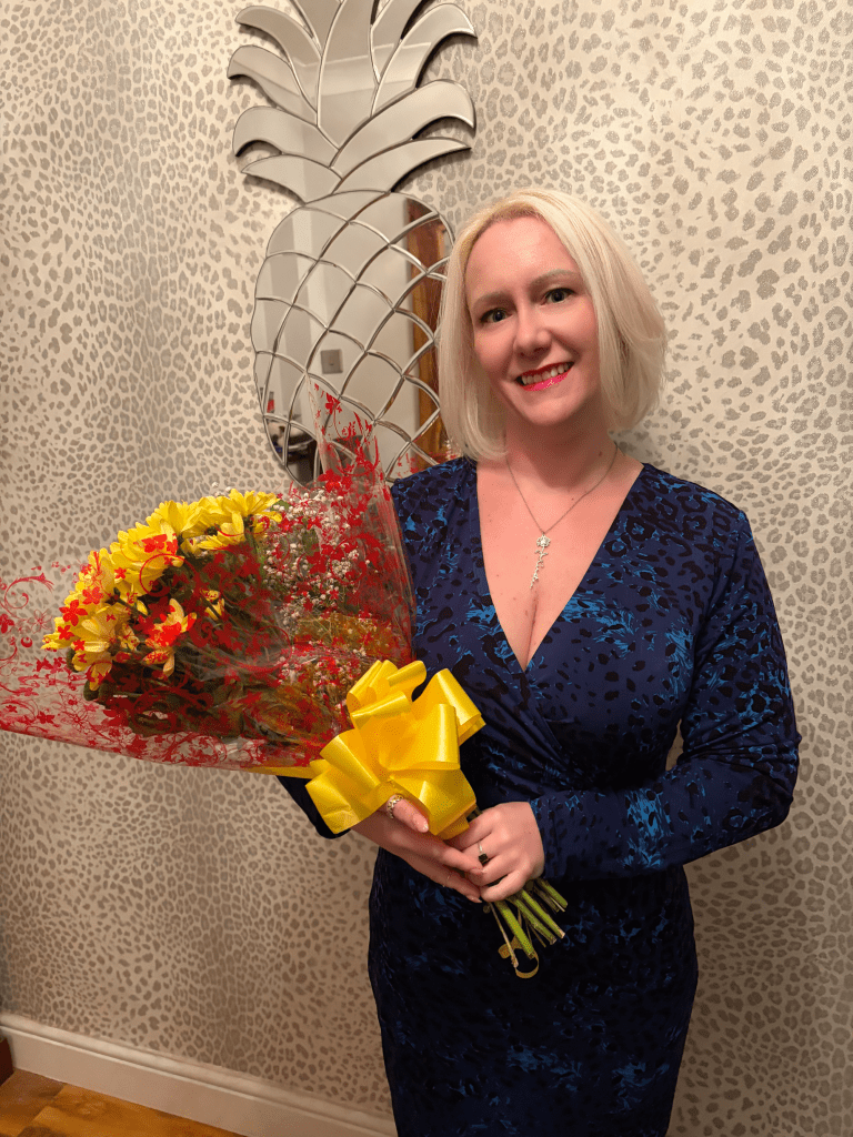 The author holding a bouquet of yellow and red flowers she received after speaking at her former school’s speech day.